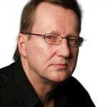 Home Close-up portrait of a serious businessman in eyeglasses against a dark background.