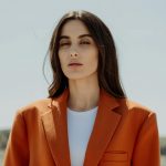 Home Portrait of a stylish woman wearing an orange blazer in natural light.