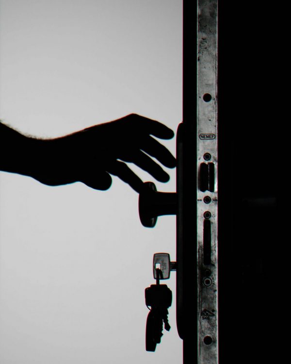 Home Silhouette of a hand about to open a door with keys in lock, symbolizing security.